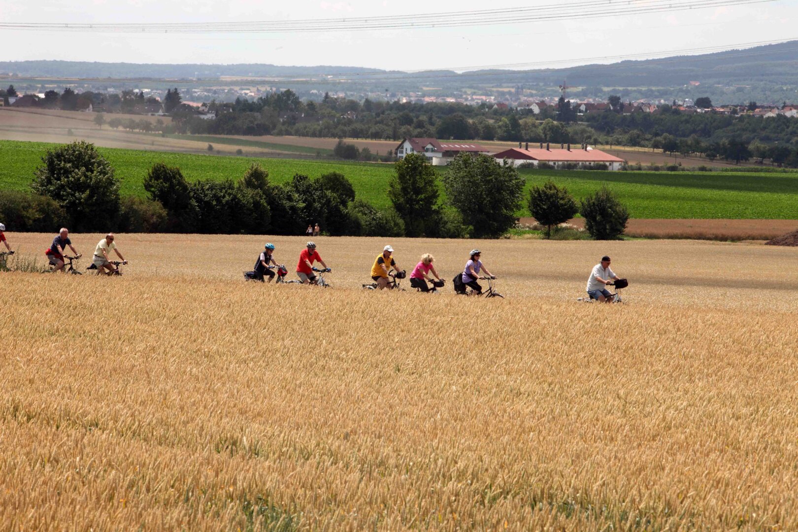 Eine Gruppe von Radfahrenden fährt auf einem Feldweg.  | © BNST GmbH