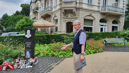 Gästeführer Hans-Ulrich Halwe vor dem Hotel Villa Grunewald, in dem Elvis wohnte. Davor steht die ihm zu Ehren errichtete Stele,  welche immer mit Blumen geschmückt ist. 